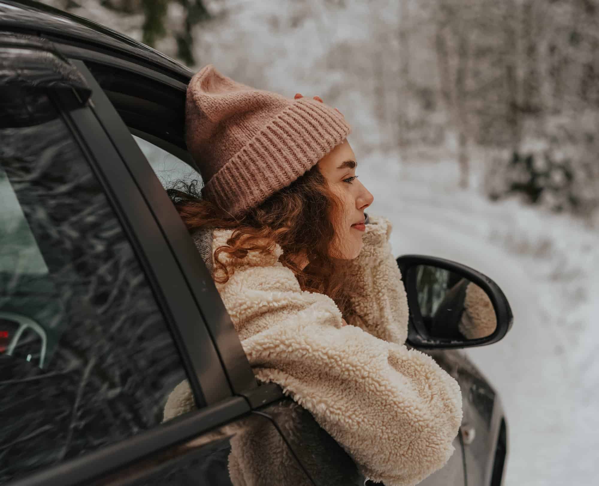 woman looking through car window during winter
