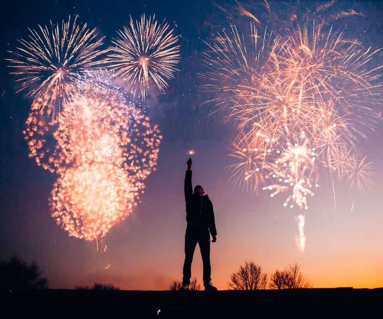 man lifting his hand up with fireworks on the background